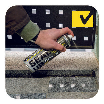 Un'immagine che mostra una mano mentre utilizza una bomboletta spray di sigillante trasparente con il marchio 'Seal Up Clear' La scena si svolge su un balcone di casa.